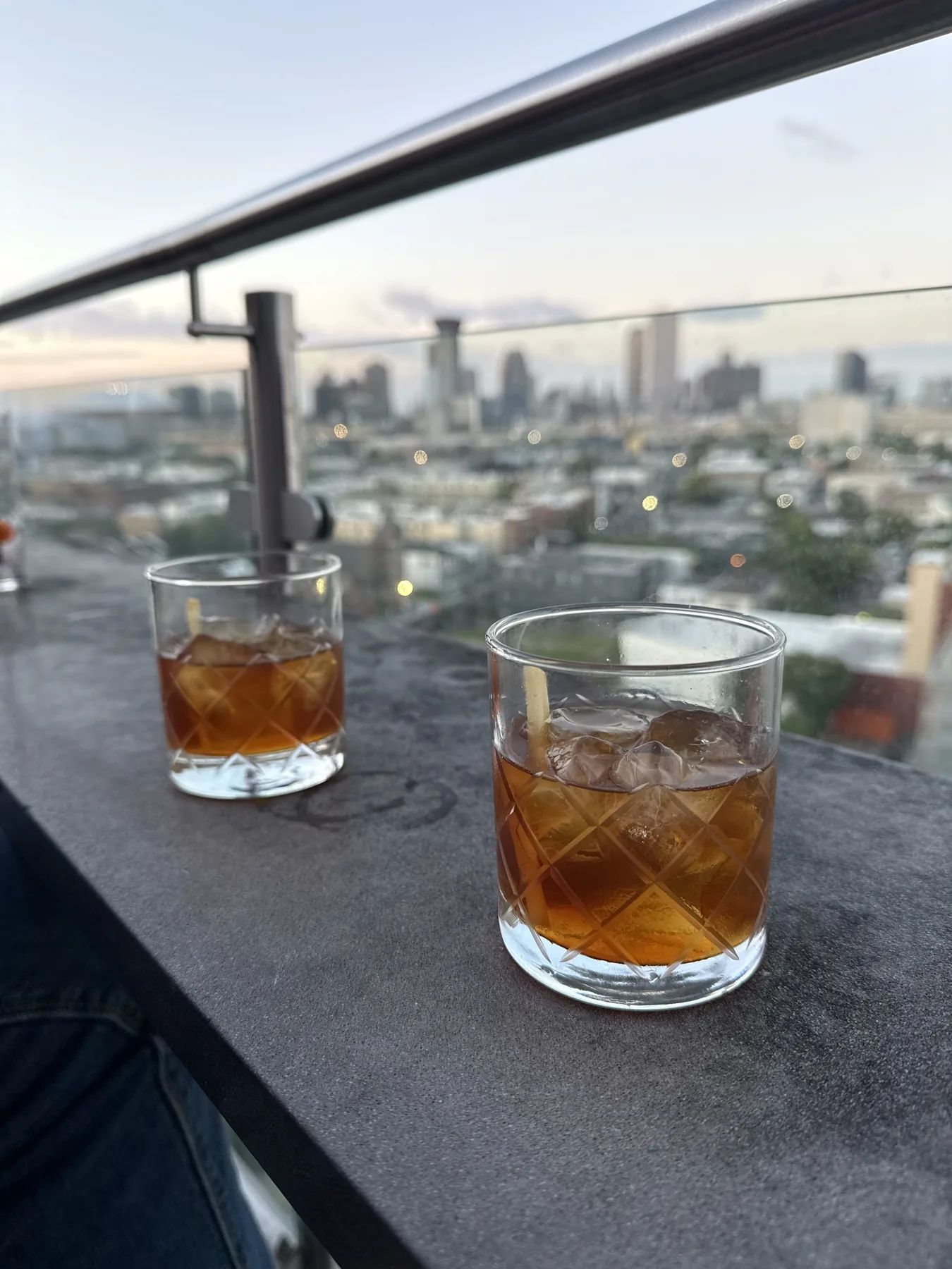 A stirred Boulevardier served over a large cube of ice with an orange peel